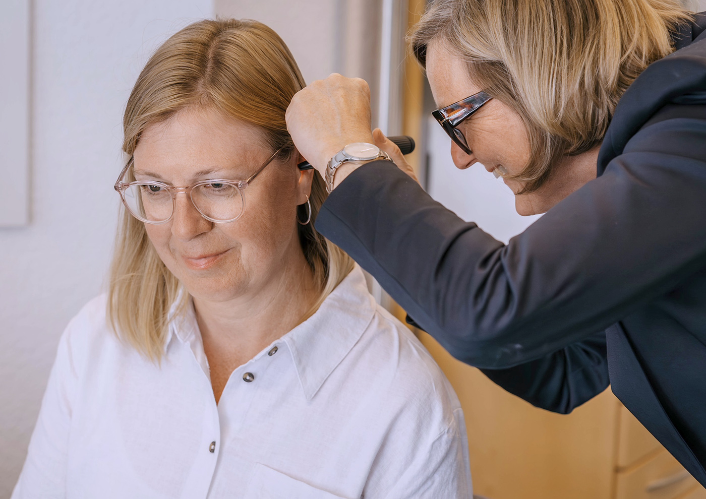 Hörgeräteakustikerin passt ein Hörgerät bei Kundin an